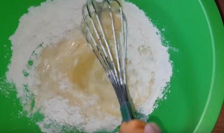 Добавете брашното и млякото към яйчената маса, разбъркайте.