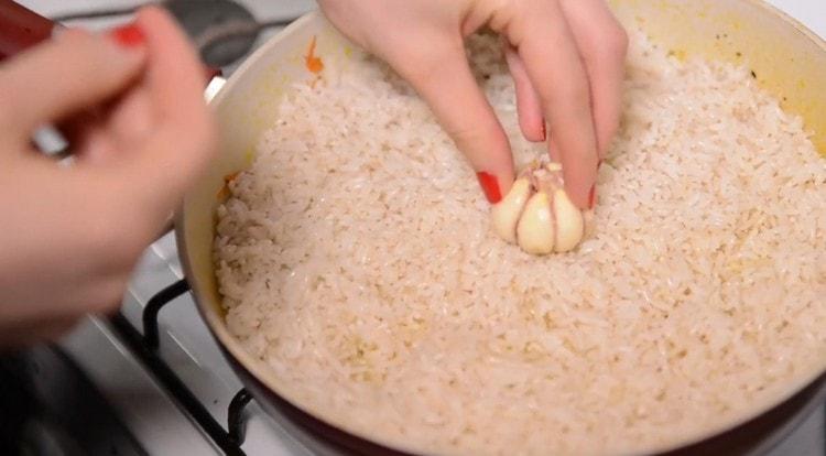 В ориза в центъра на тигана лепим глава чесън.