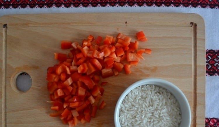 Измиваме ориза и нарязваме чушките на чушки.