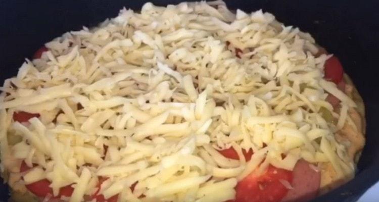 Поръсете пицата със сирене.