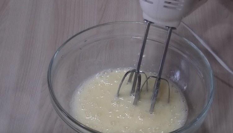 Разбийте яйцата със захарта с миксер.