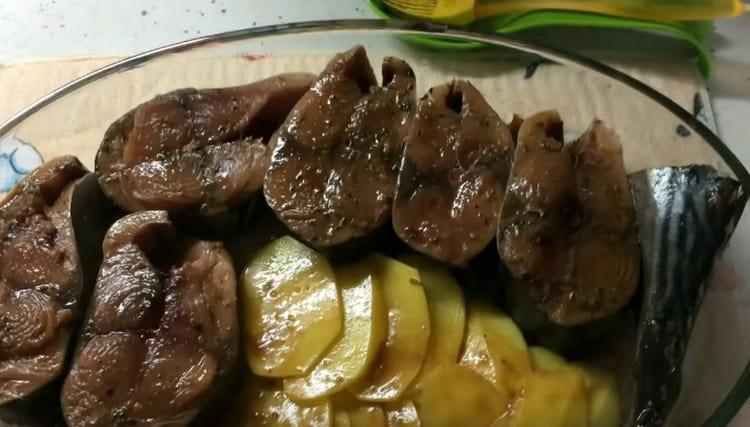Разпределяме парчетата риба тон и картофи в тава за печене, като предварително сме смазали дъното й с марината.
