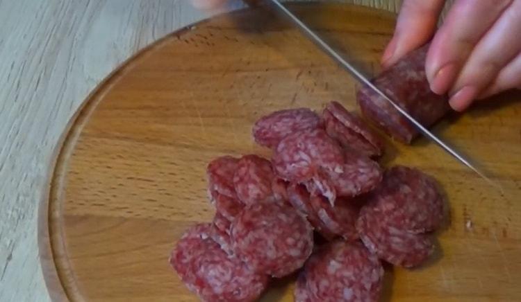 За да направите пица с бутер тесто, нарежете наденицата