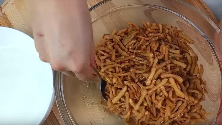 Сипете сиропа в пърженото тесто и бъркайте бързо.