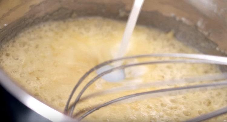 На следващо място, въвеждаме мляко и смесваме масата, разбивайки бучките.