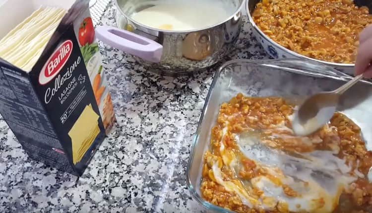 В долната част на формата сложете малко сос Болонезе и бешамел, разбъркайте.