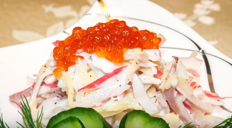 При сервиране салата с калмари и ракови пръчици се украсява с червен хайвер.