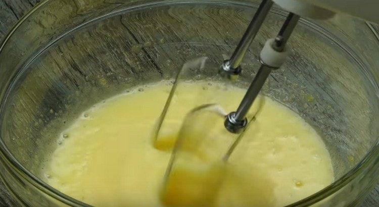 Разбийте яйцата със захарта с миксер.