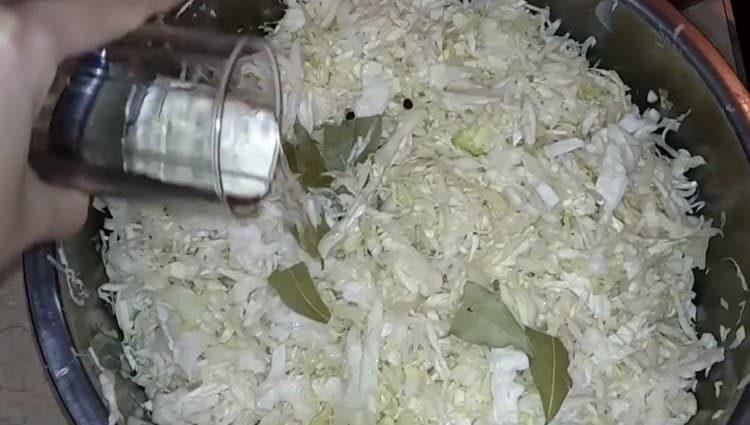 Добавете дафинов лист, черен пипер и оцет към зелето.