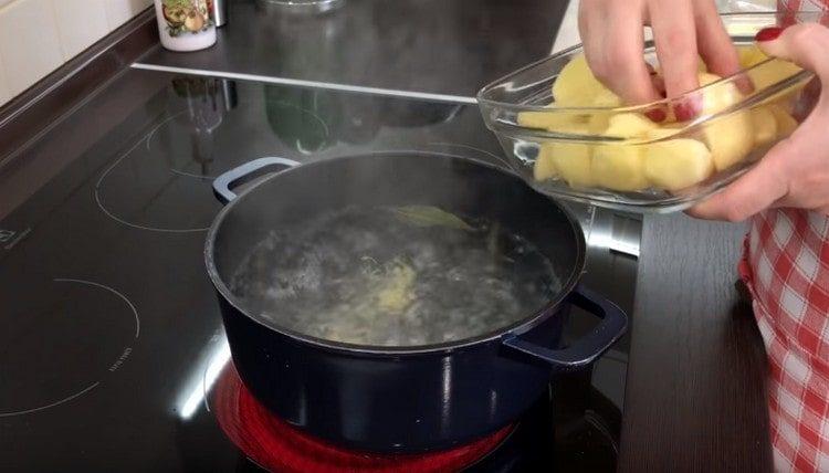 Почистваме картофите, нарязваме ги на парчета и ги поставяме във преварена вода.