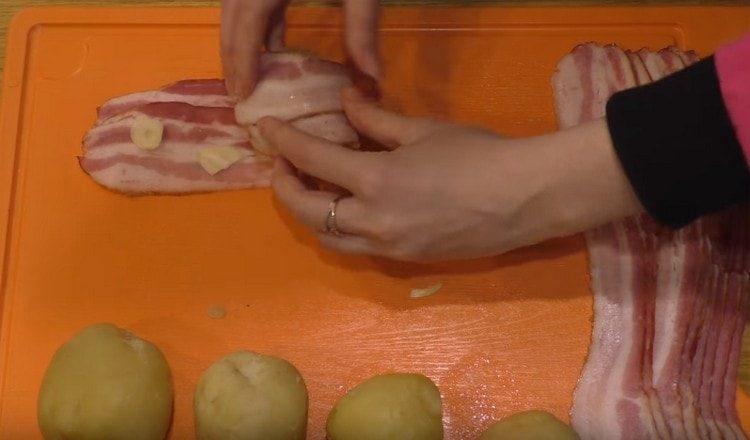 Сложете чесъна върху бекона и увийте картофите в него.