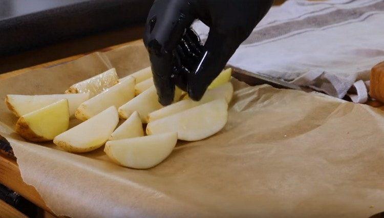 полагайки лист за печене с пергамент, поставете картофени клинове.