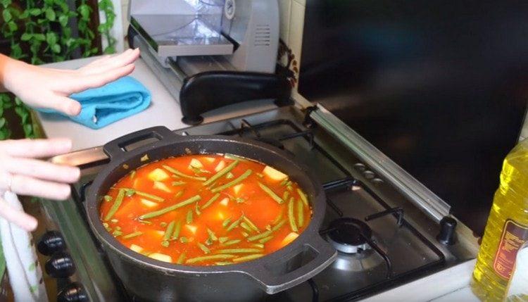 Добавете картофите и боба към казана, налейте вода, добавете сол, черен пипер и грах и задушете ястието.
