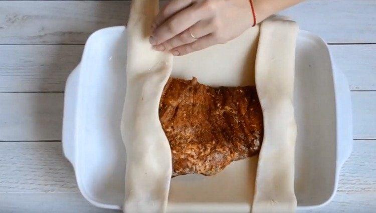 Разпределяме месото върху тестото, увиваме го с плик.